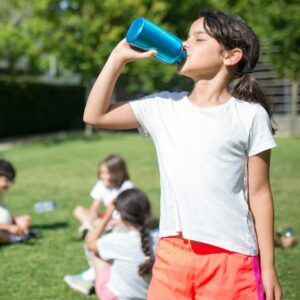 Bambina beve acqua durante attività all'aperto